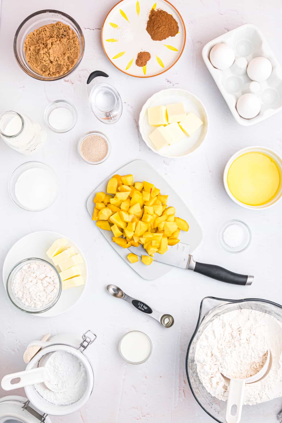 The ingredients for peach cobbler cinnamon rolls are placed on a white surface.