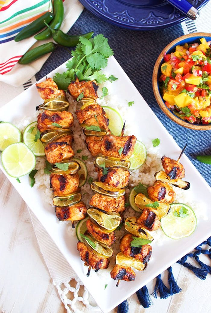 Overhead shot of chili lime chicken kabobs on a white platter.
