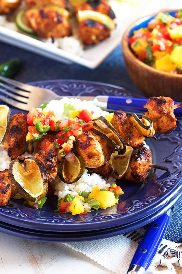 Chicken kabobs on a blue plate with rice.