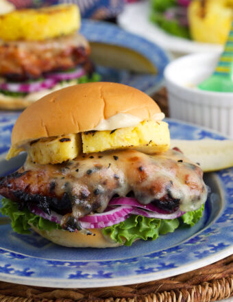 Grilled teriyaki chicken sandwich on plate with grilled pineapple and toppings