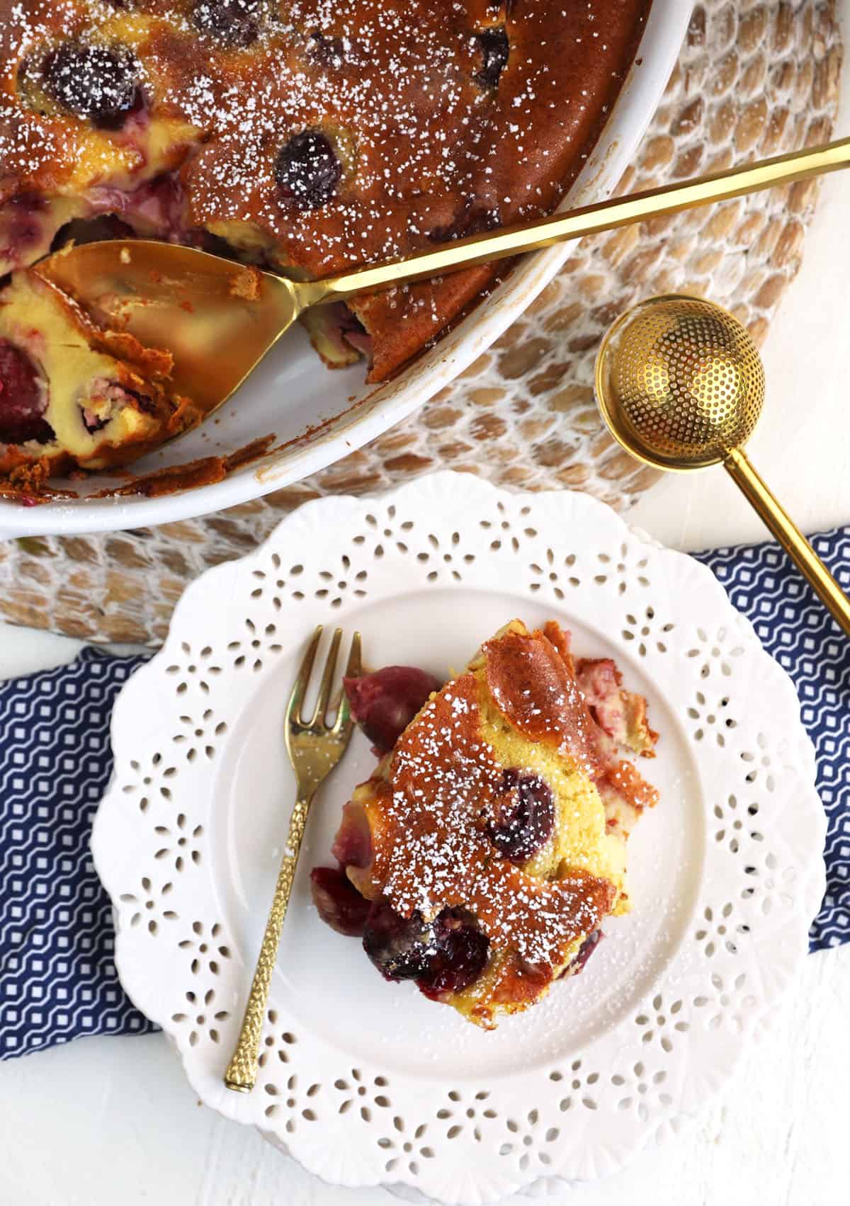 Overhead view of cherry clafoutis on plate and in baking dish