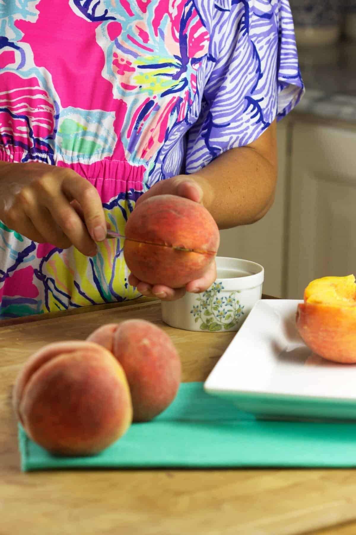 Woman cutting a fresh peach in half.