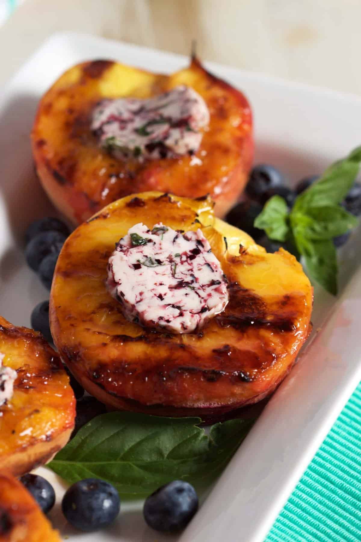 Grilled peaches on a platter topped with blueberry butter