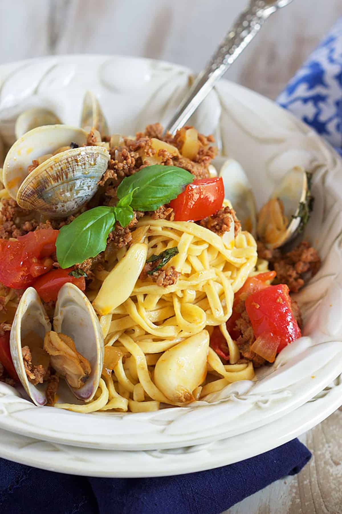 Linguine with clams in a white bowl with a silver fork.