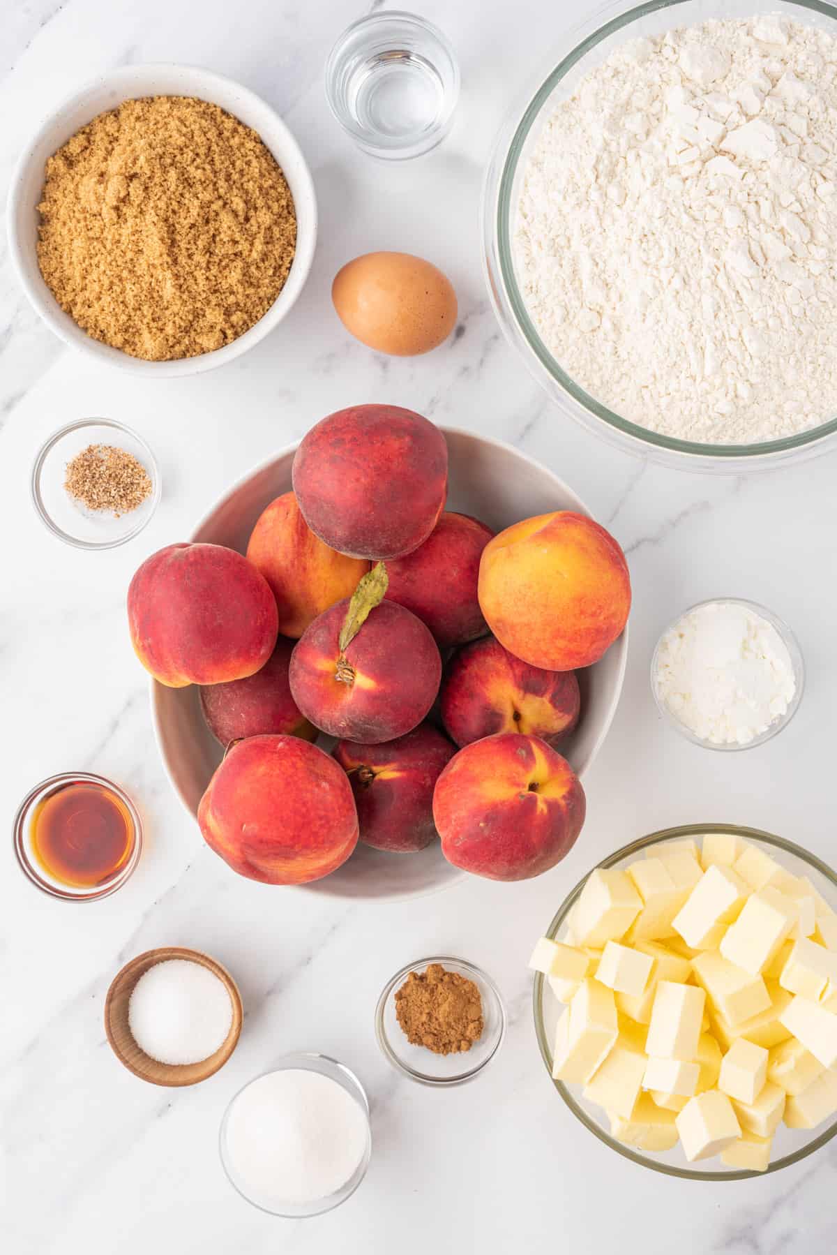 The ingredients for peach slab pie are placed on a white countertop. 