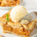 A piece of pie is being eaten with a fork. There's a scoop of vanilla ice cream on top.