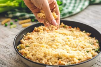 Bread crumbs being sprinkled on tuna noodle casserole.