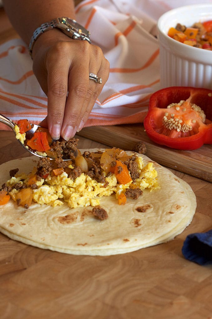 Chorizo and eggs being spooned into a tortilla.