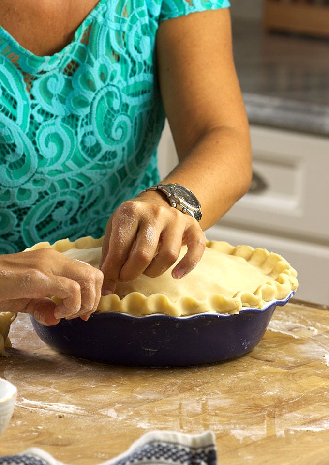 The edges of the pie crust are being crimped. 