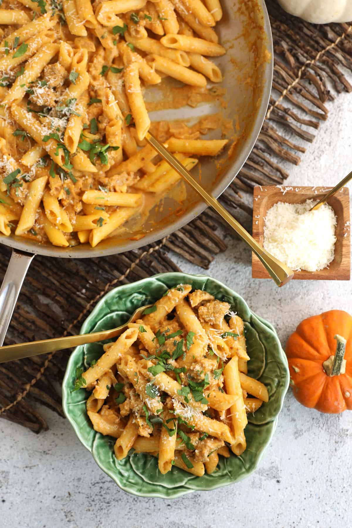 Overhead view of pumpkin pasta in skillet and bowl