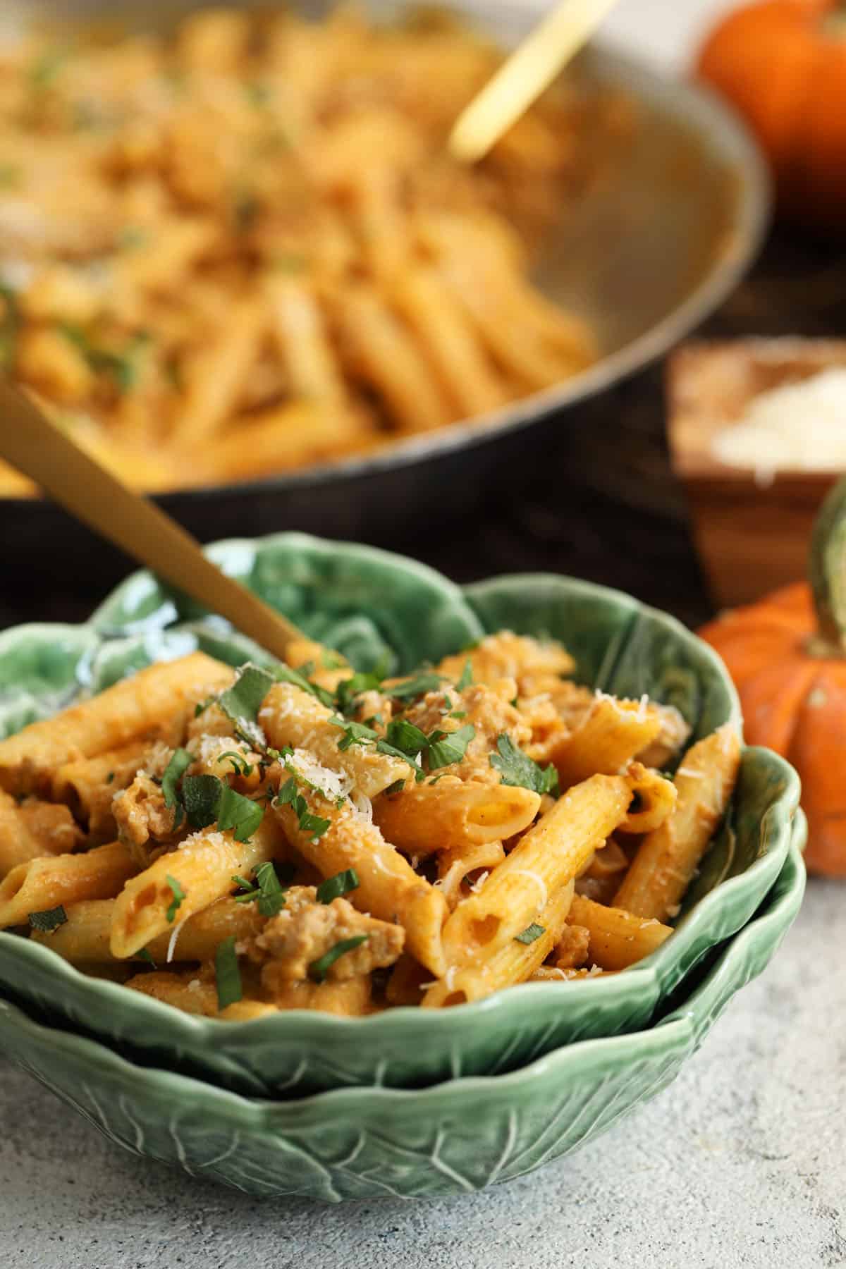 Pumpkin pasta in bowl, with skillet of pasta in background