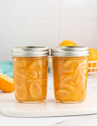 Two jars of marmalade are placed next to each other on a white surface.