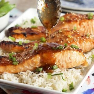 Sweet Chili Orange Glazed Salmon on a bed of rice with sauce being drizzled over top.
