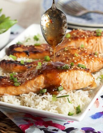 Sweet Chili Orange Glazed Salmon on a bed of rice with sauce being drizzled over top.