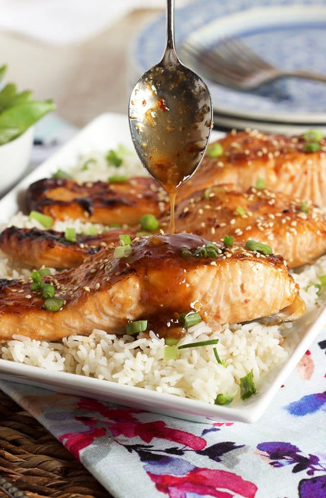 Sweet Chili Orange Glazed Salmon on a bed of rice with sauce being drizzled over top