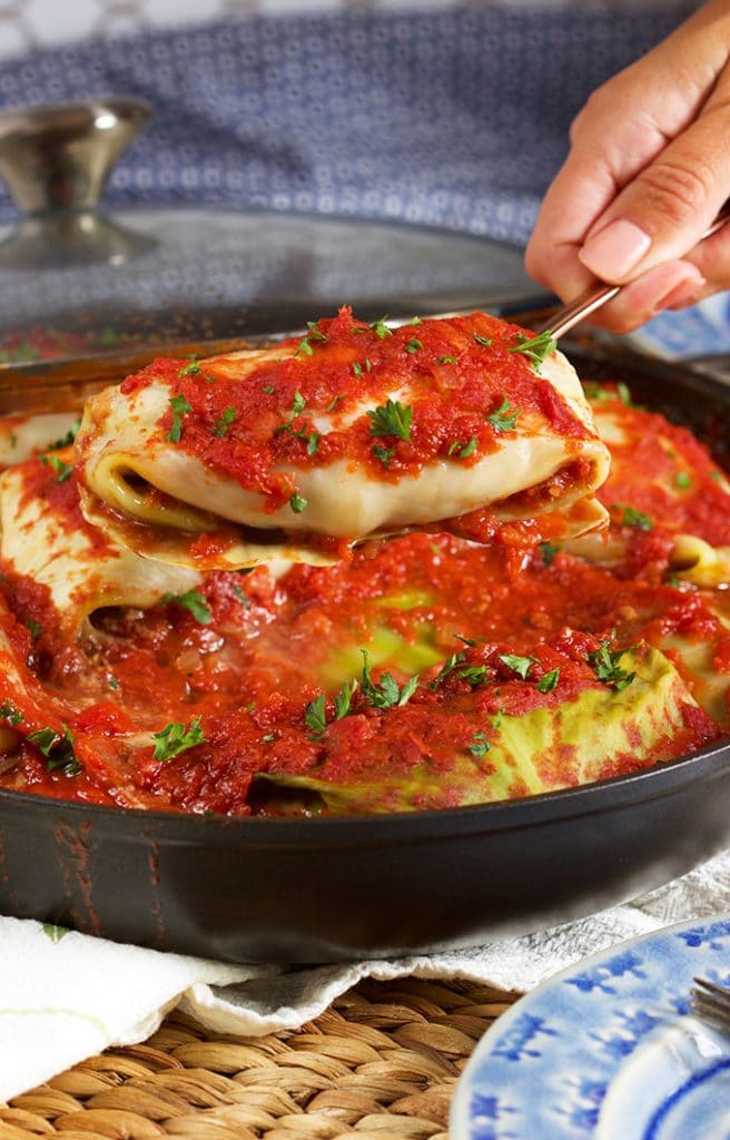 Stuffed cabbage rolls being served from a black pan.