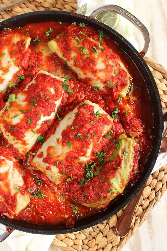 Overhead shot of stuffed cabbage rolls in a black le crest pan on a wicker placemat.