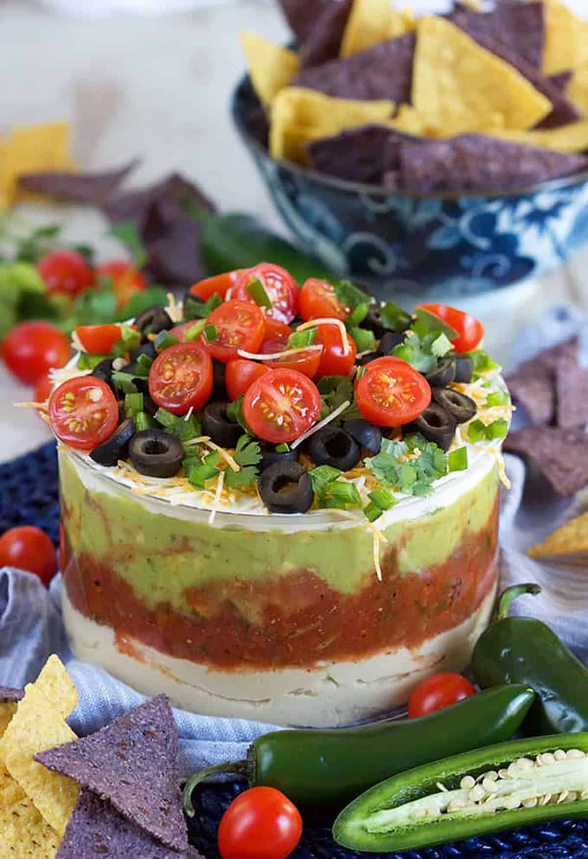 7 layer mexican dip in a glass bowl with chips in the background.