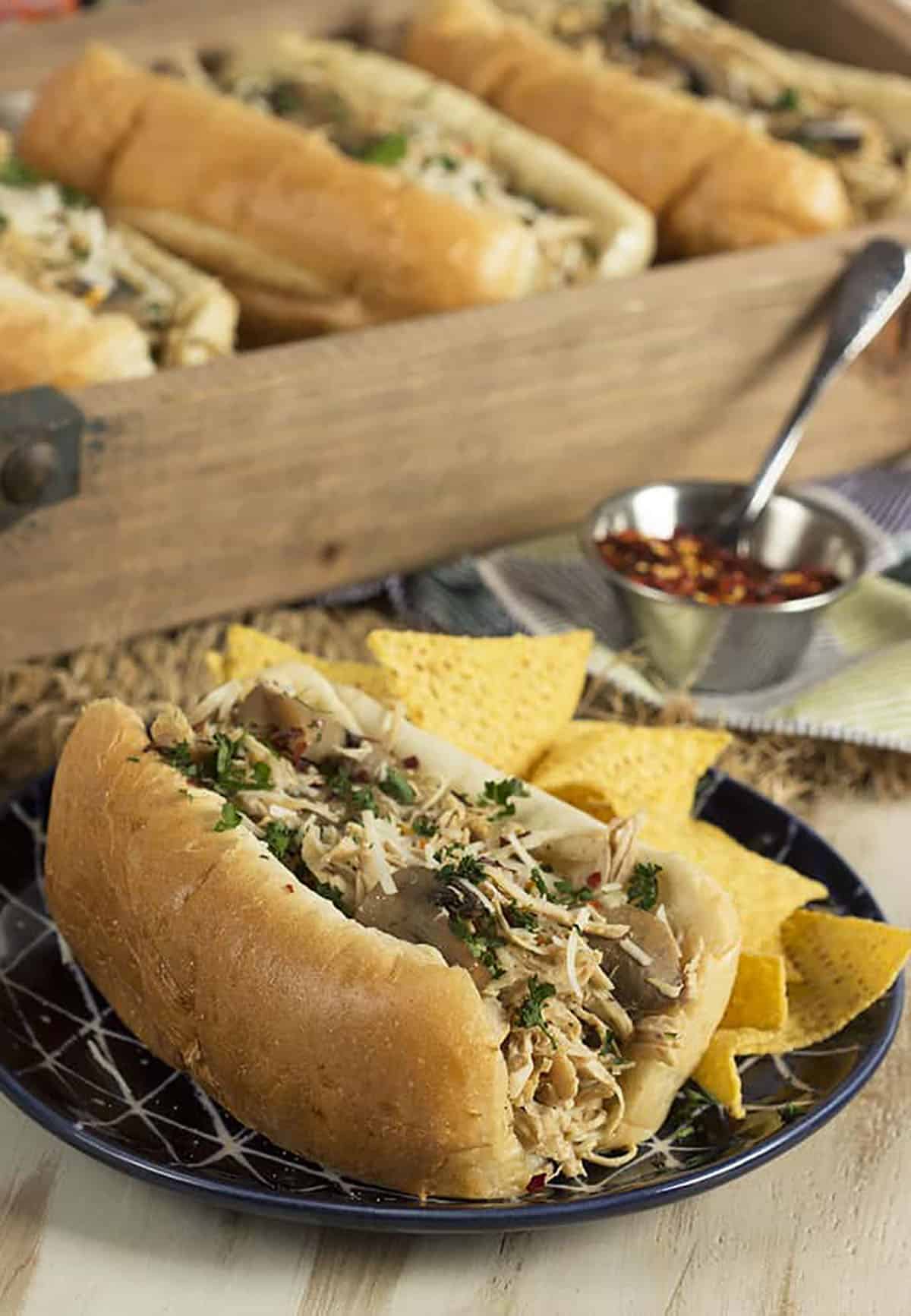 Chicken cheesesteak on a blue plate with tortilla chips.