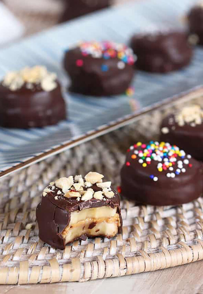 Chocolate covered banana bites with a bite out of one on a wicker place mat.