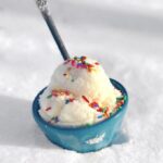 Blue bowl of snow ice cream with sprinkles in the snow.