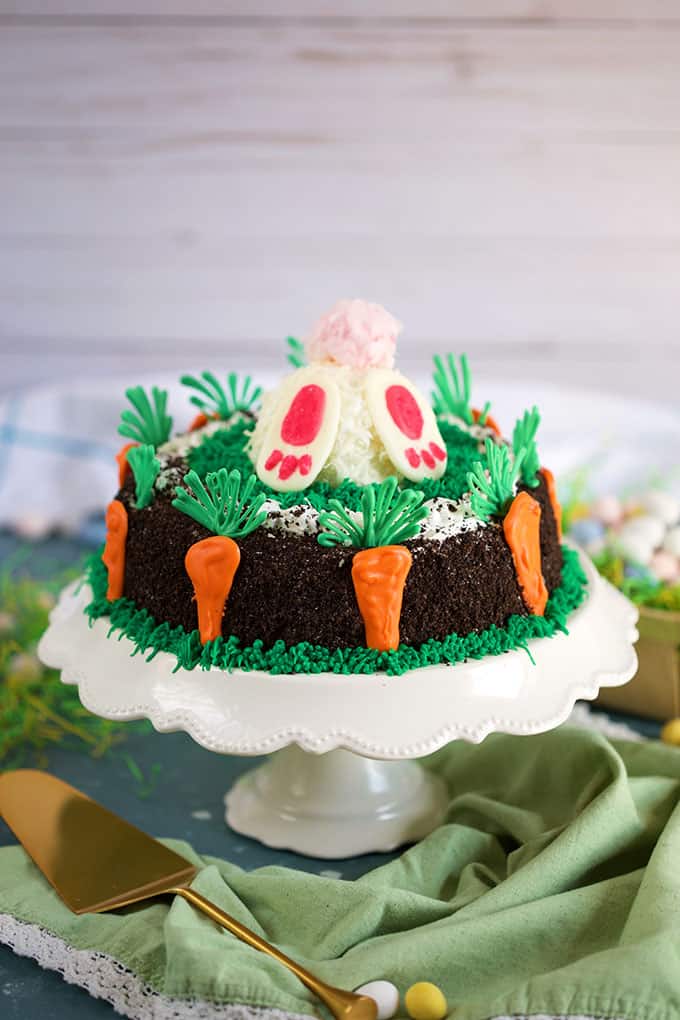 Oreo Ice Cream Cake decorated with chocolate carrots and a vanilla ice cream bunny butt on a cake plate from TheSuburbanSoapbox.com