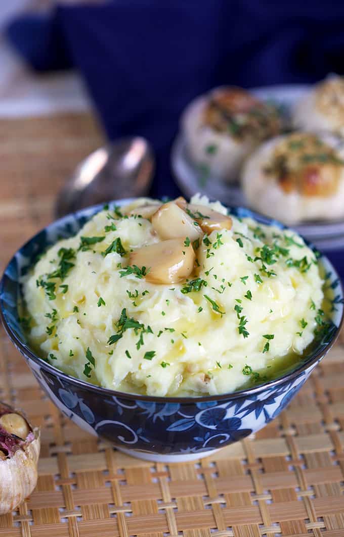 Roasted Garlic Mashed Potatoes in a blue and white bowl with parsley. TheSuburbanSoapbox.com