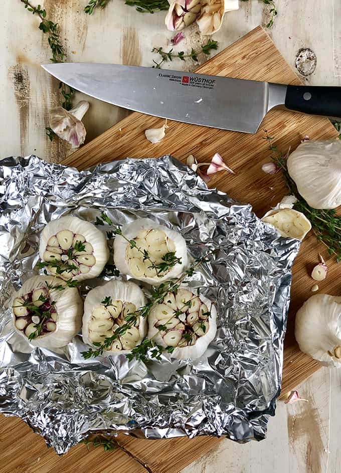 Sliced Garlic bulbs with thyme in foil with chef's knife. | TheSuburbanSoapbox.com