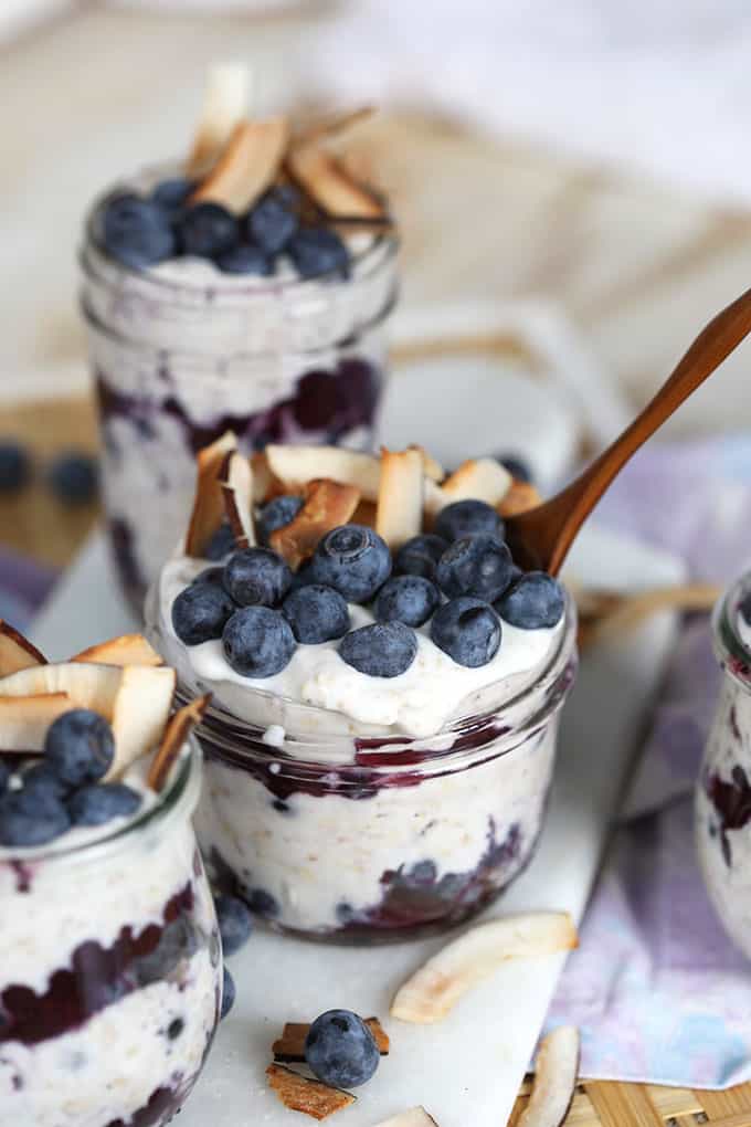 Blueberry and Coconut Overnight Oats recipe in a jar with a wooden spoon. From TheSuburbanSoapbox.com
