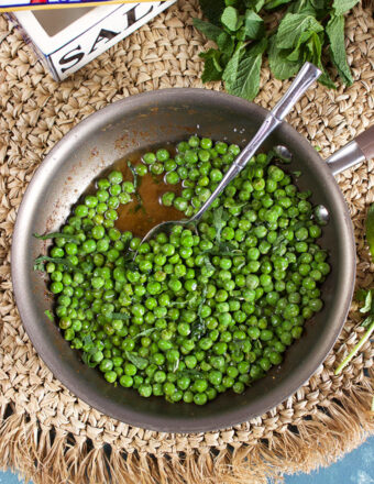 Brown Butter Sweet Peas with Mint in a skillet with a spoon and a salt box from TheSuburbanSoapbox.com
