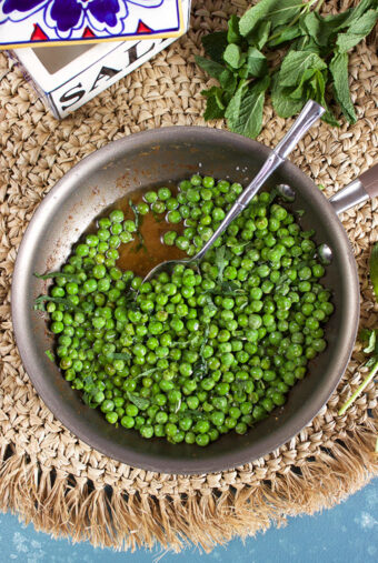 Brown Butter Sweet Peas with Mint in a skillet with a spoon and a salt box from TheSuburbanSoapbox.com