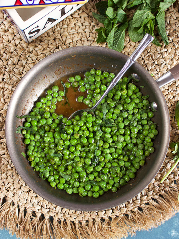 Brown Butter Sweet Peas with Mint in a skillet with a spoon and a salt box from TheSuburbanSoapbox.com