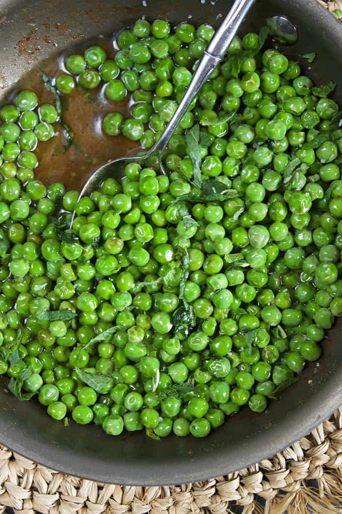 Green peas in a skillet with a silver spoon from TheSuburbanSoapbox.com