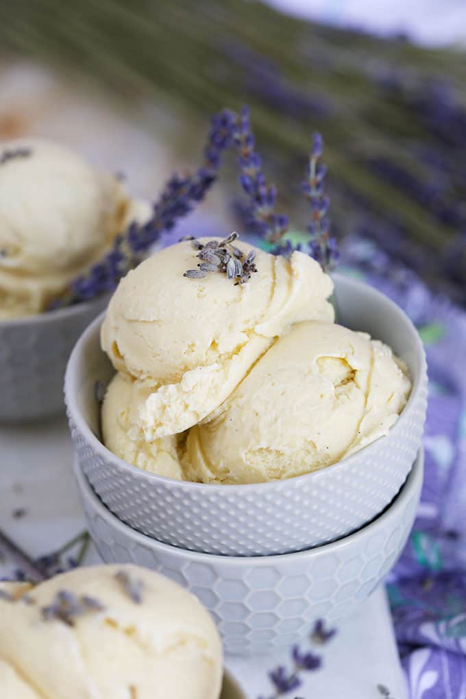 Two scoops of Lavender Ice Cream in a stack of gray bowls with lavender stems from TheSuburbanSoapbox.com