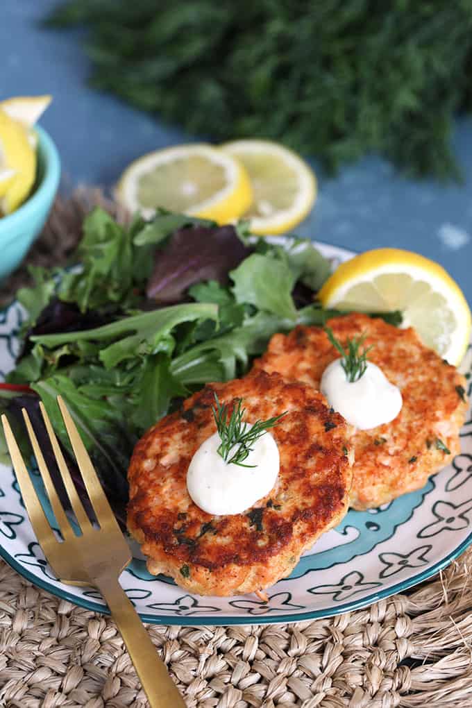 Salmon Cakes recipe with Lemon Dill Sauce on a plate on a wicker placemat from TheSuburbanSoapbox.com