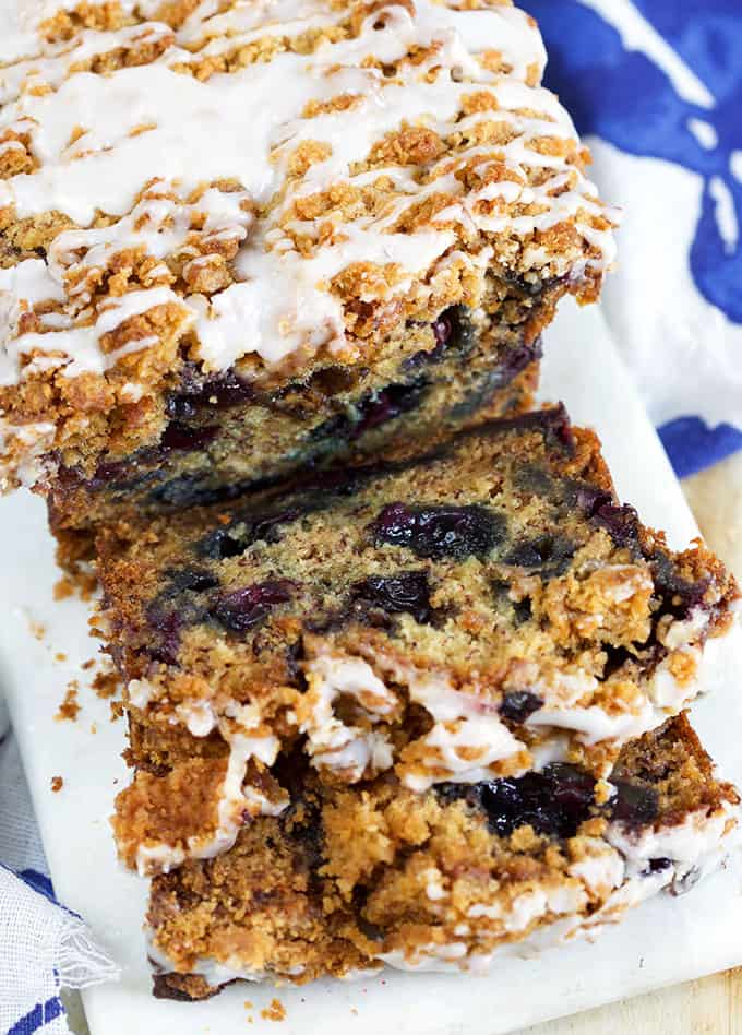 Blueberry Banana Bread with streusel and glaze sliced on a marble board with a blue napkin from TheSuburbanSoapbox.com