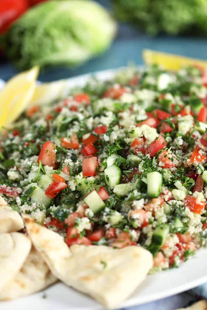 Side shot of Cauliflower Rice Tabbouleh Salad on a white platter with pita bread from TheSuburbanSoapbox.com