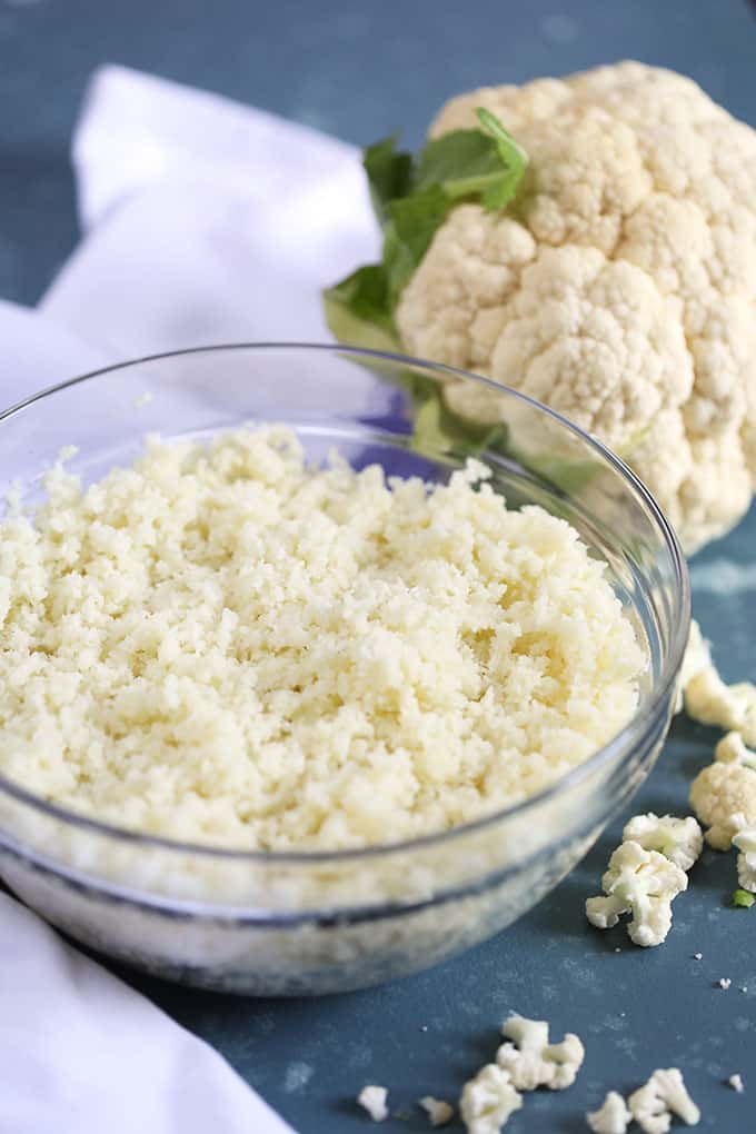 Glass bowl of cauliflower rice on a blue background from Thesuburbansoapbox.com