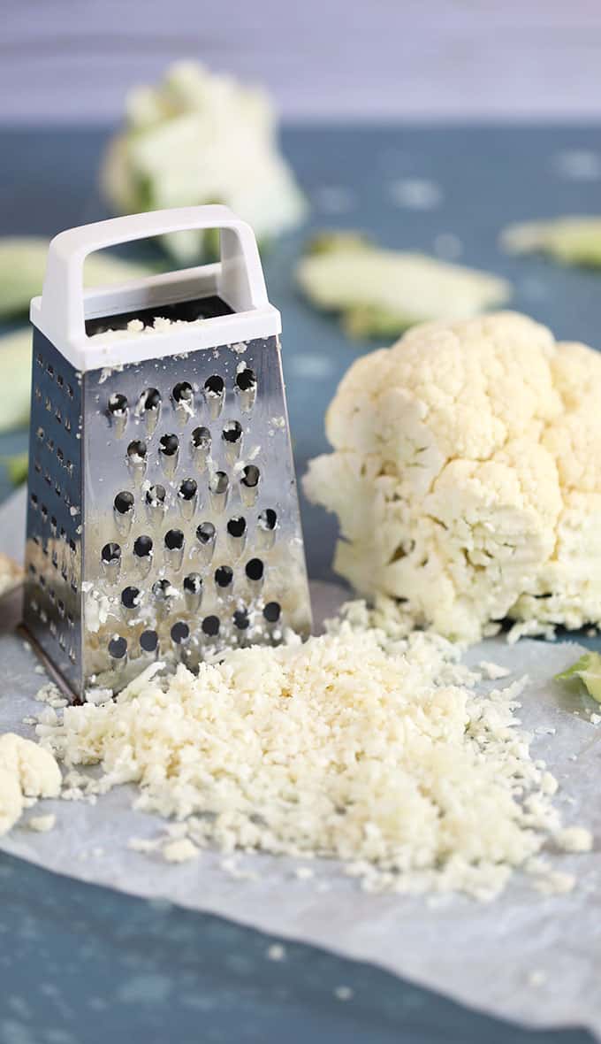 Cauliflower rice made with a box grater with a head of cauliflower on a blue background from TheSuburbanSoapbox.com