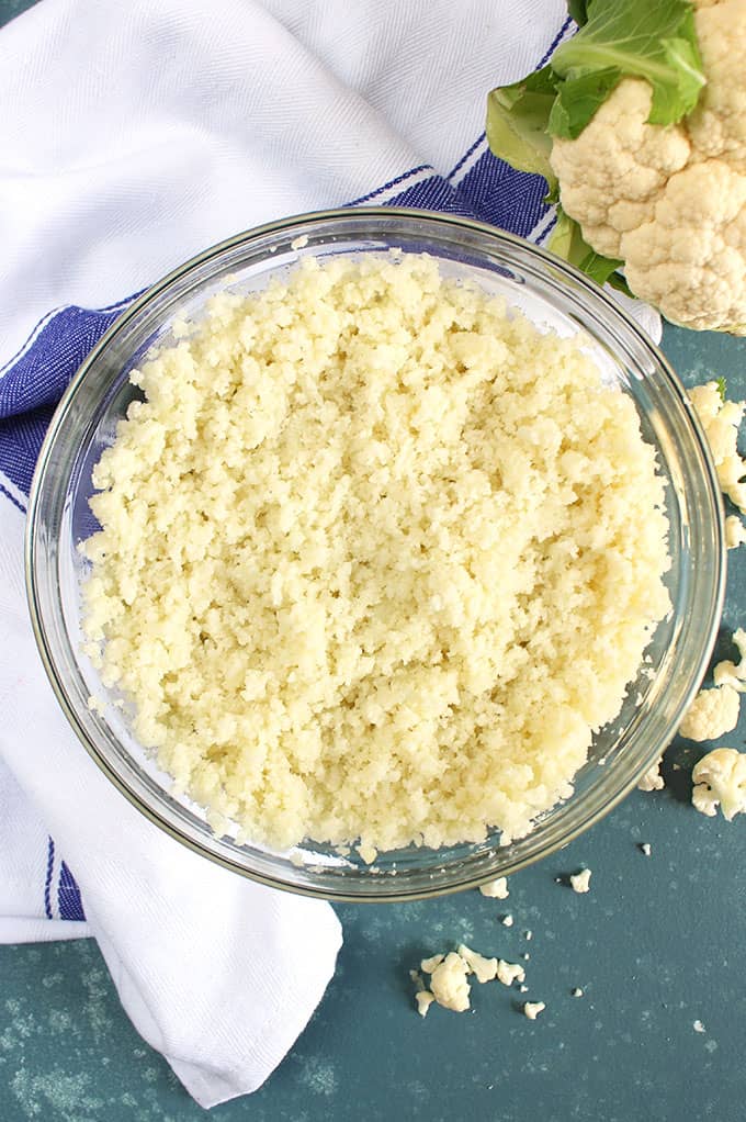 Overhead shot of cauliflower rice in a glass bowl on a blue background from TheSuburbanSoapbox.com