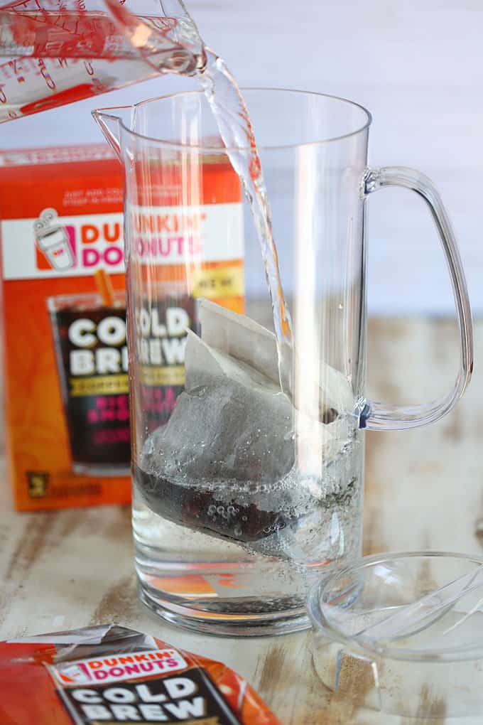 Clear pitcher with Dunkin Donuts Cold Brew packet and water being added to the pitcher from TheSuburbanSoapbox.com