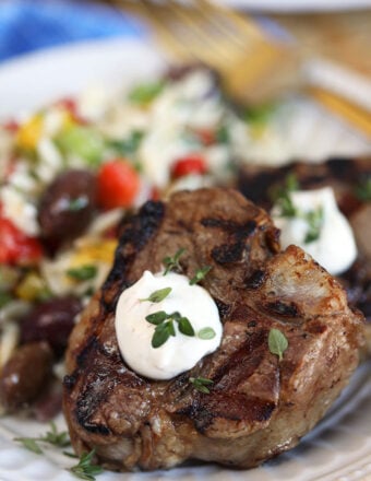 Close up shot of grilled lamb chops with goat cheese sauce on a white plate from TheSuburbansoapbox.com