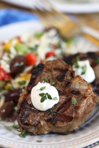 Close up shot of grilled lamb chops with goat cheese sauce on a white plate from TheSuburbansoapbox.com