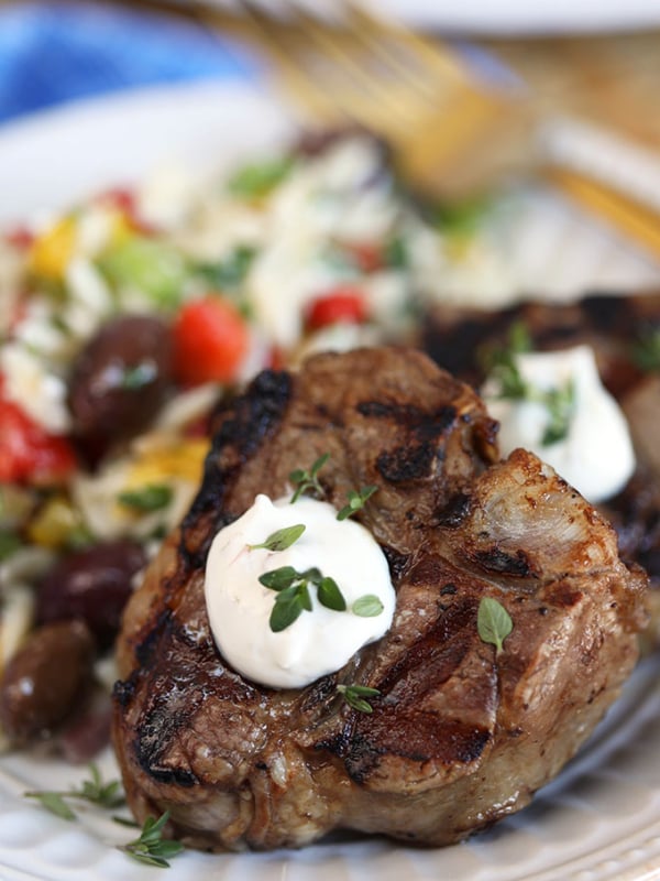 Close up shot of grilled lamb chops with goat cheese sauce on a white plate from TheSuburbansoapbox.com