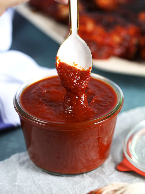 Honey Chipotle Barbecue Sauce recipe in a glass jar with a white spoon dipped into it. From TheSuburbanSoapbox.com