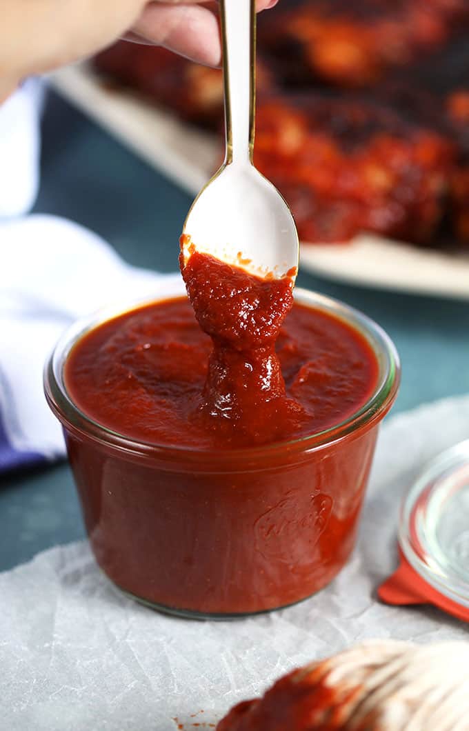 Honey Chipotle Barbecue Sauce recipe in a glass jar with a white spoon dipped into it. From TheSuburbanSoapbox.com