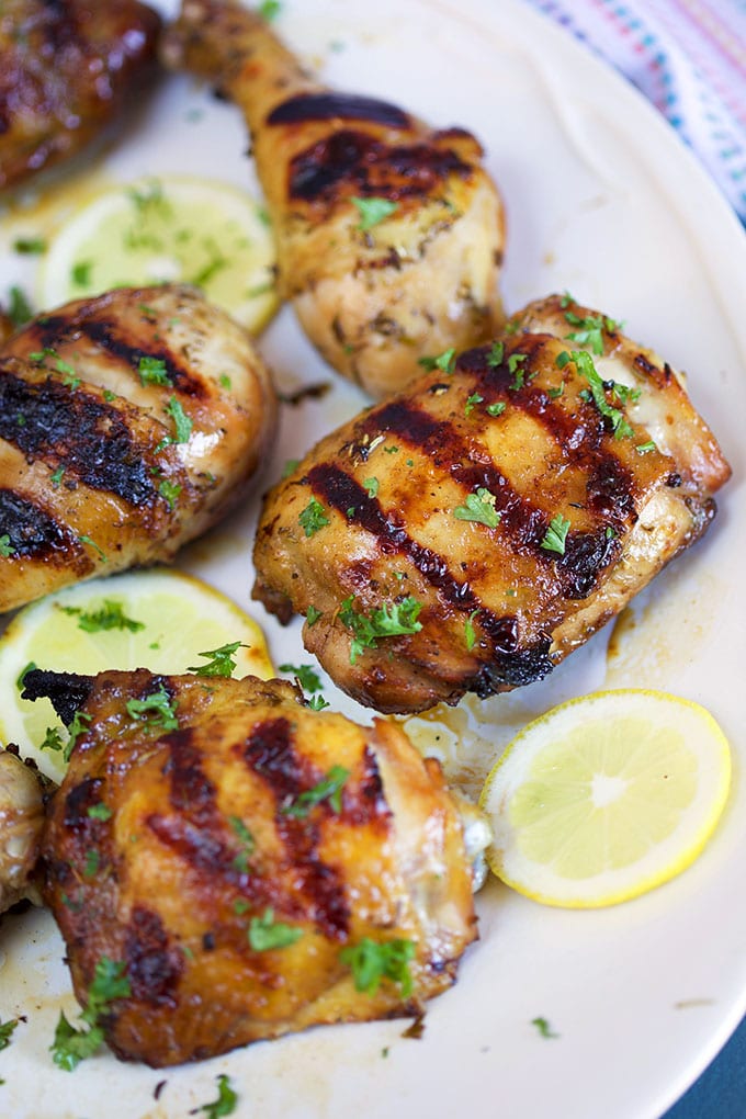 Grilled chicken thighs on a white platter with lemon slices from TheSuburbanSoapbox.com