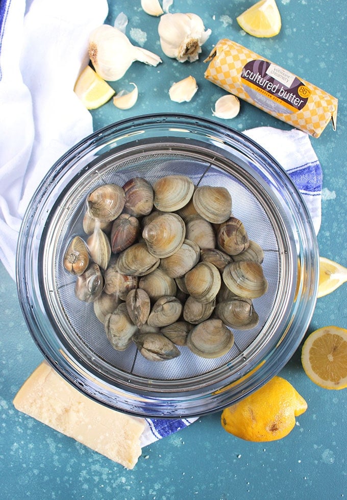Clams soaking in a glass bowl with water.