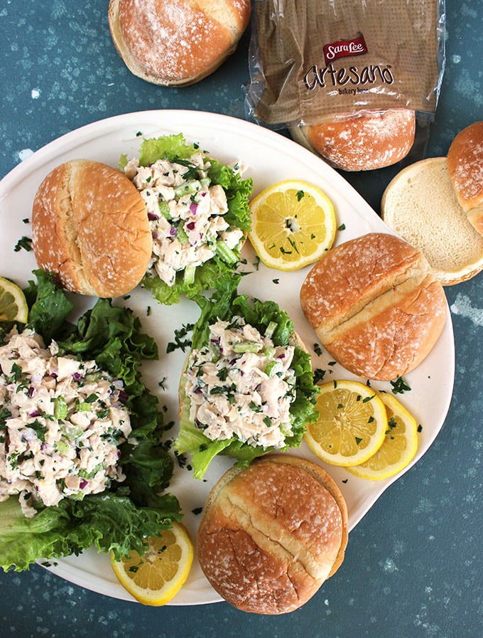 Overhead shot of lemon tarragon chicken salad sandwiches on a white platter with a blue background from TheSuburbansoapbox.com