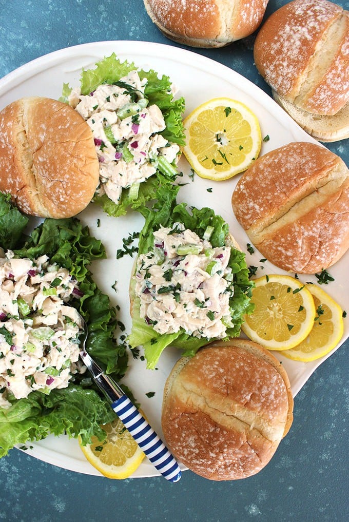 Overhead shot of lemon tarragon chicken salad on rolls on a white platter with a blue background from TheSuburbansoapbox.com